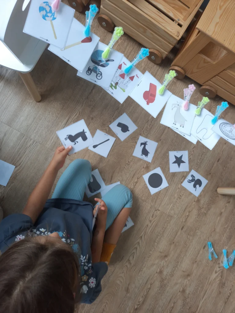 Dziecko dopasowujące cienie do ilustracji podczas ćwiczeń logopedycznych rozwijających percepcję wzrokową i słownictwo.